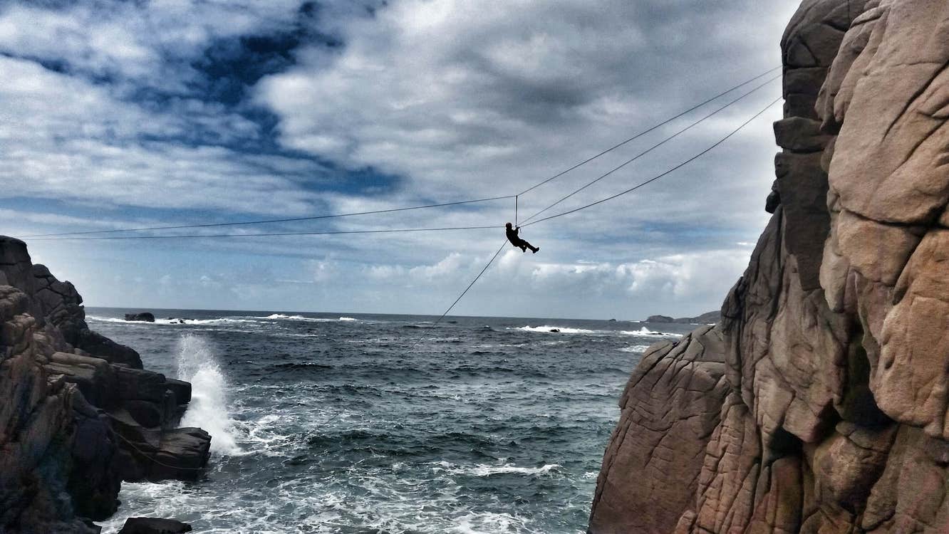 A man abseiling between rocks over water
