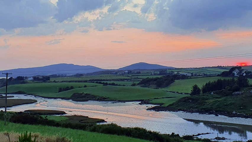 The sun setting in the distance with a river visible in the foreground