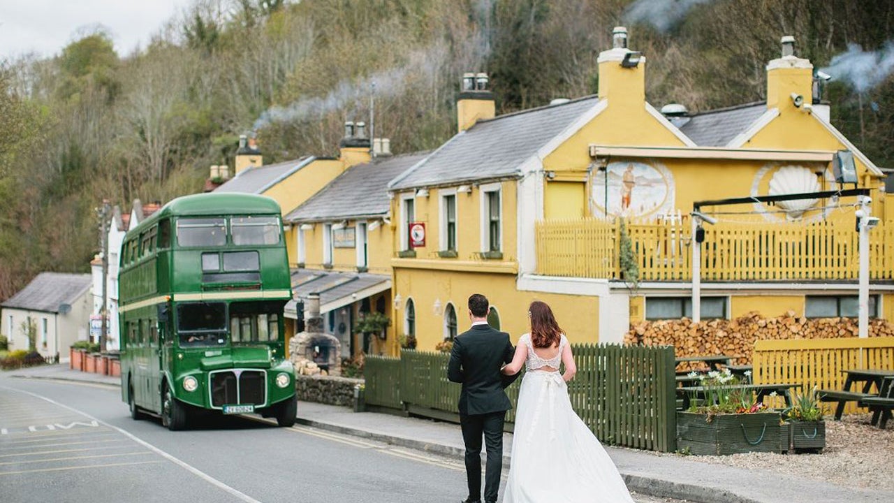 Bride and groom walking towards Wright's Anglers Rest where a green double decker bus is parked outside