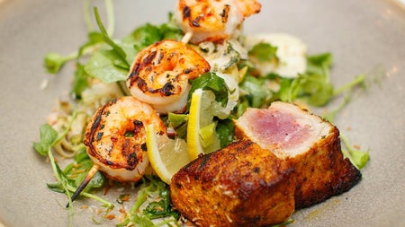 A plate of seared scallops and tiger prawn satay from the a la carte menu at Bay Restaurant