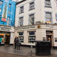 A cream coloured three storey building and shopfront of Claddagh Jewellers on a busy street