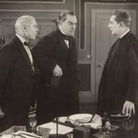 Three men in 19th century clothing are talking in a room.