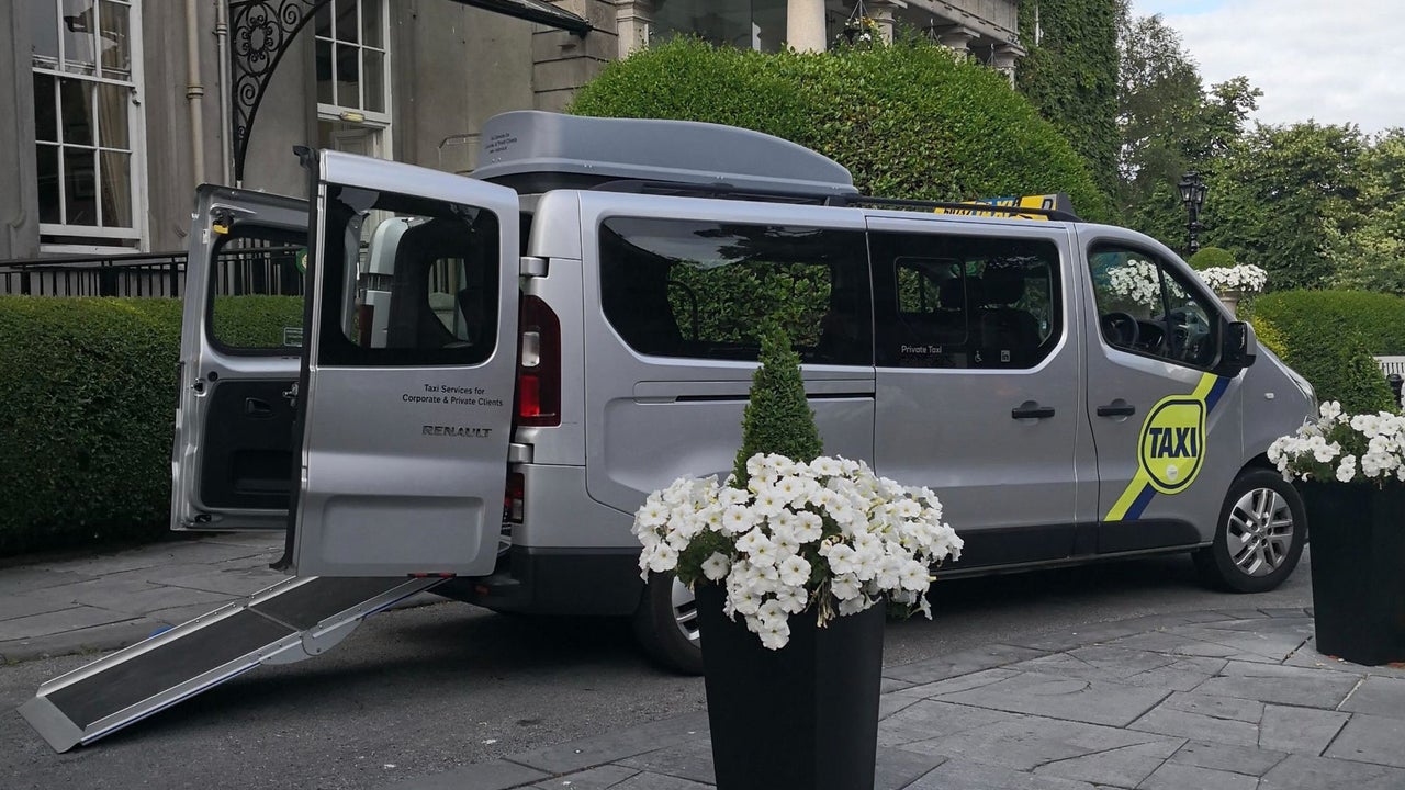 A wheelchair accessible taxi parked outside a hotel with Dublin Wheelchair Taxis
