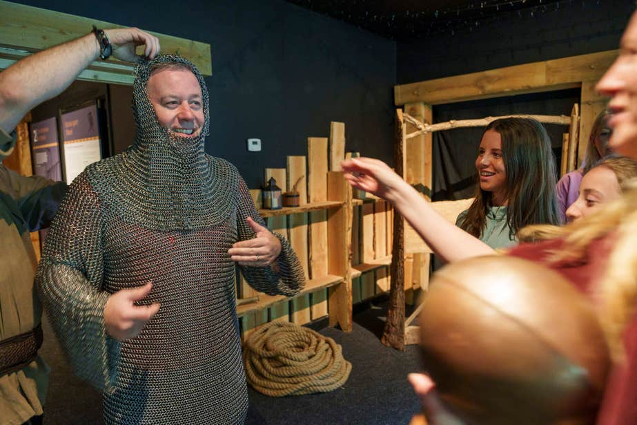 Man wearing chain mail with family at the Knights and Conquests Heritage Centre.