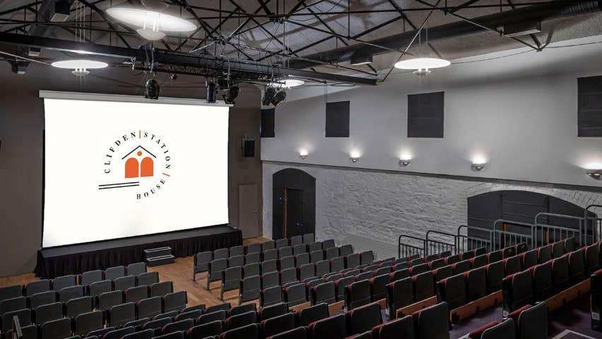 A theatre with tiered seating facing a cinema screen