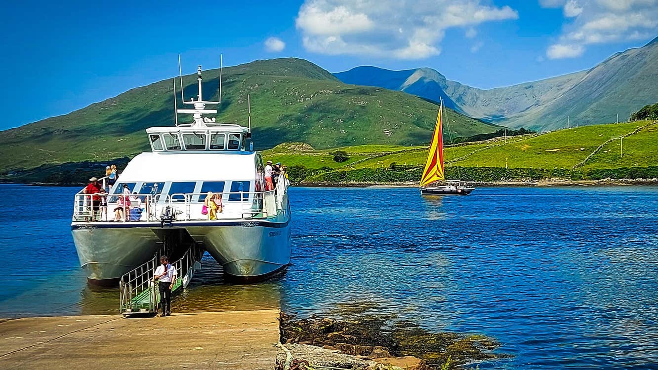 White boat docked at a slipway with green mountains in the background