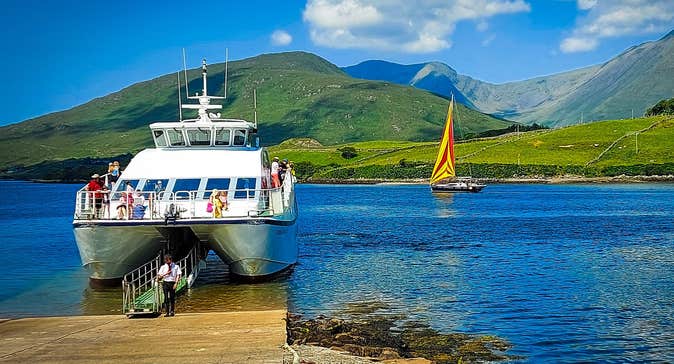 White boat docked at a slipway with green mountains in the background