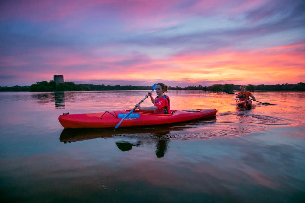 Two people kayaking on Lough Oughter, Cavan at sunset in Ireland's Ancient East.