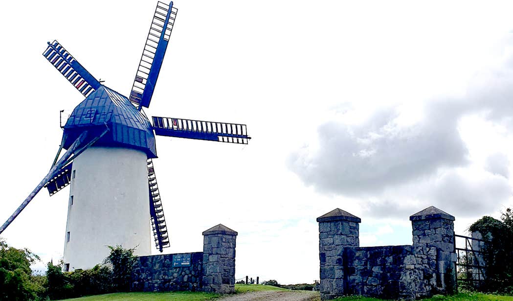 Blue windmill behind a stone wall at Skerries Mills in Dublin.