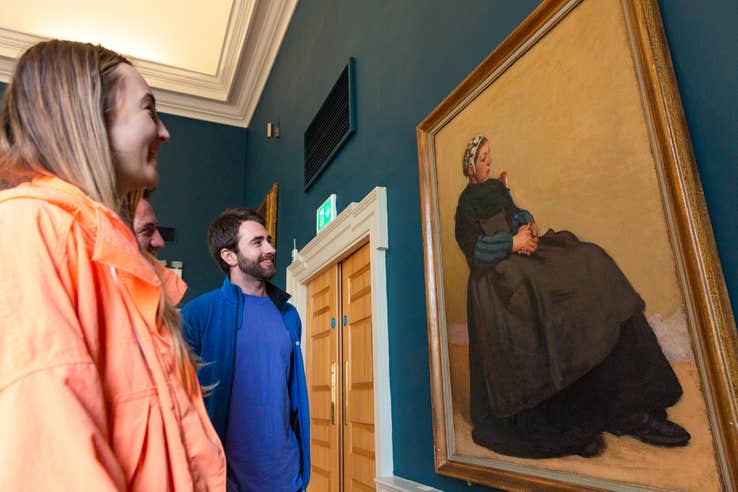 Three people viewing a piece of art in The Hunt Museum in Limerick