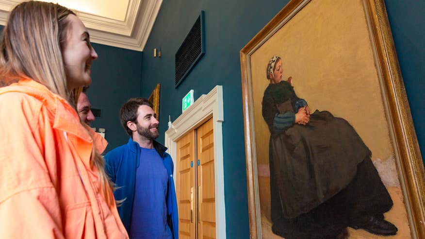 Three people viewing a piece of art in The Hunt Museum in Limerick