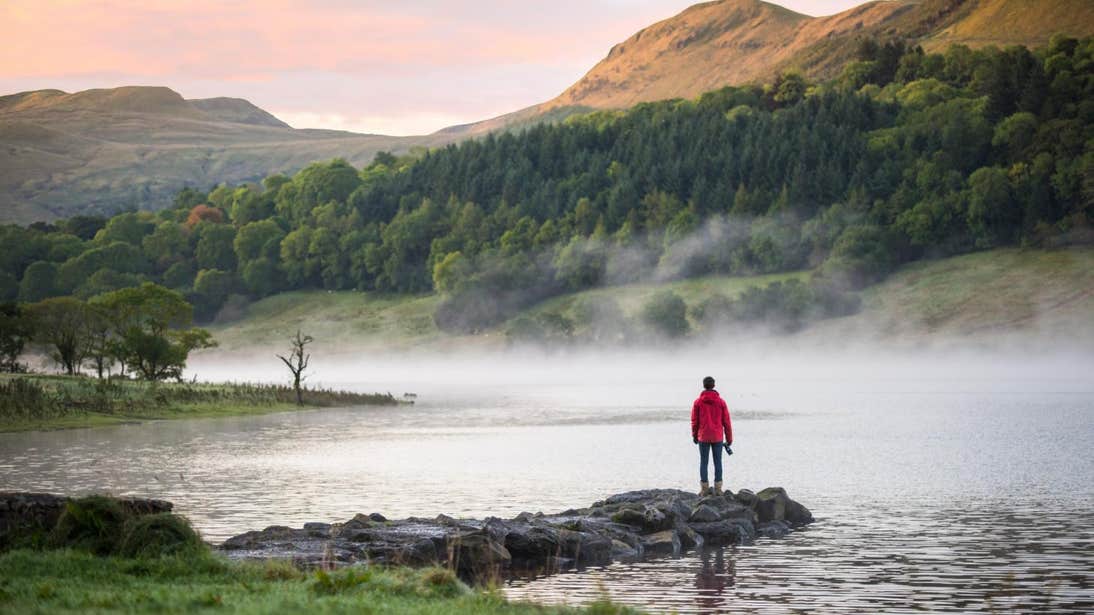 Person standing on rocks looking out across the water at Glencar Lake in Leitrim