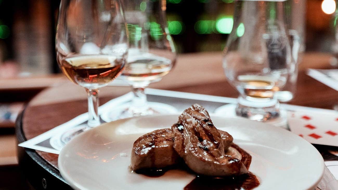 Whiskey glasses and a white plate of food on a wooden table