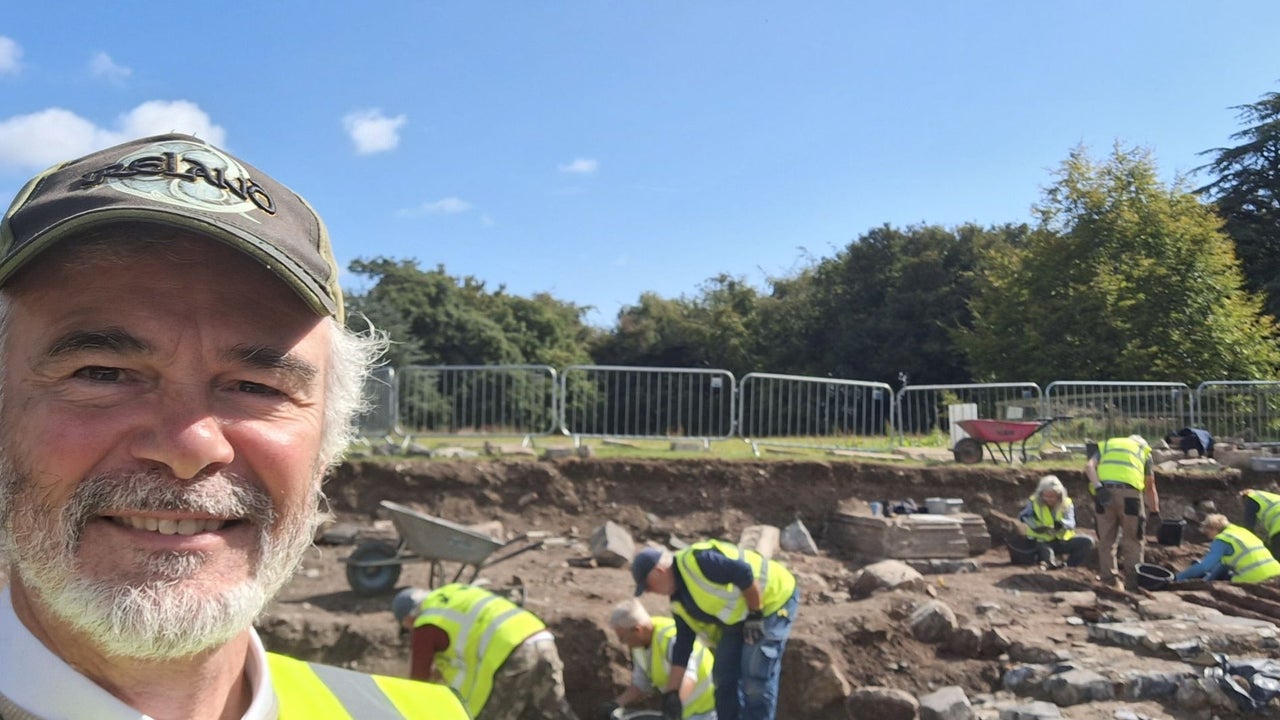 A view of an open excavation trench with several people wearing high visibility vests