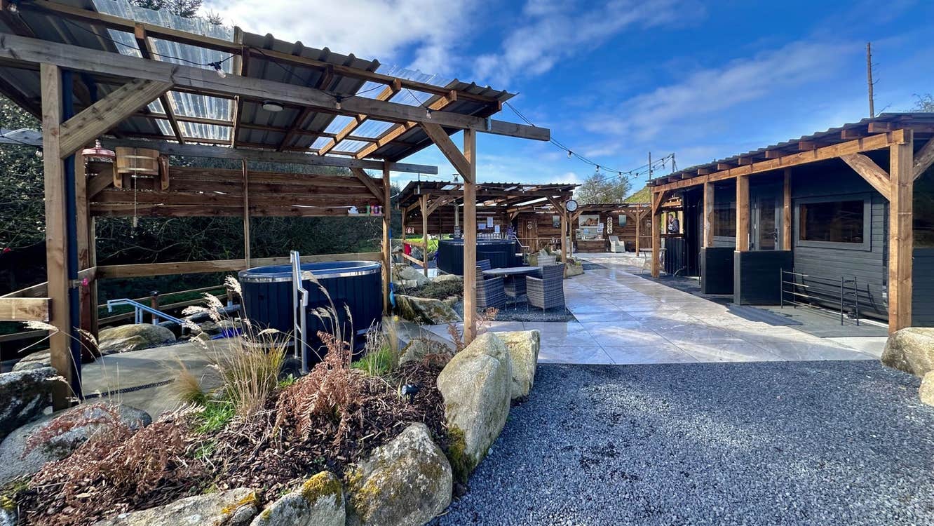 Pathway into an area with mobile sauna units on the right and mobile hot tubs on the left