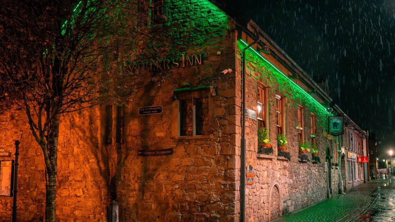 Exterior of a stone building at night with green strip lighting underneath the roof