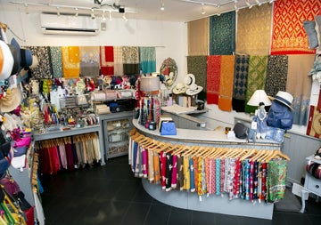 Shop floor with scarfs and clothes on hangers and fashion accessories on shelves