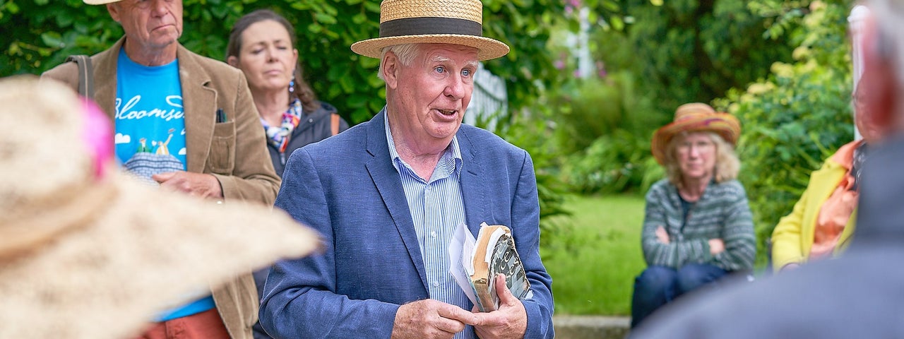 Dalkey Castle Bloomsday Guided Walk, a man in straw hat is talking to small, scattered group outdoors.