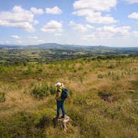 A hiker looking out onto a grassy landscape with hills in the distance