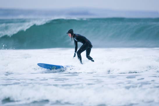 Person surfing on a blue board wearing a full wetsuit in Strandhill, Sligo