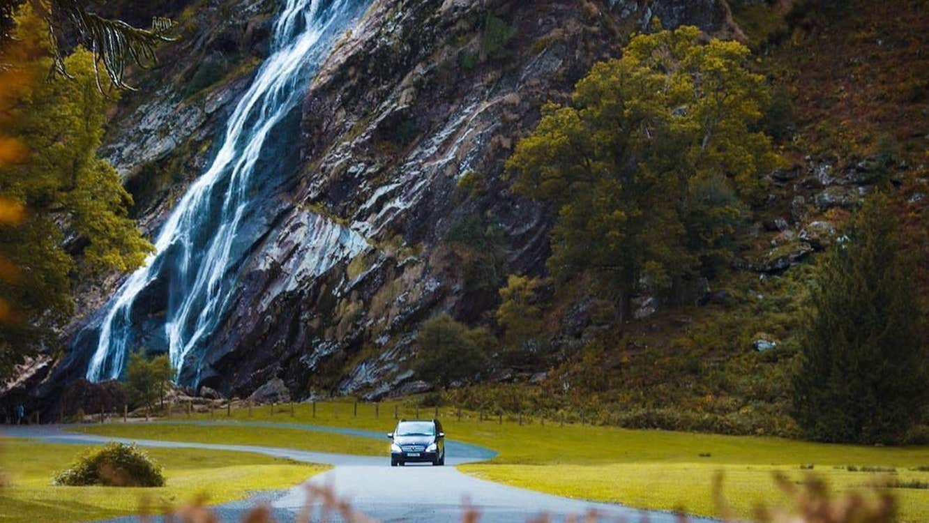 Car driving on a road with a waterfall in the background