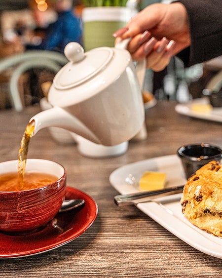 Kilkenny Café view of tea being poured into a tea cup with a fruit scone
