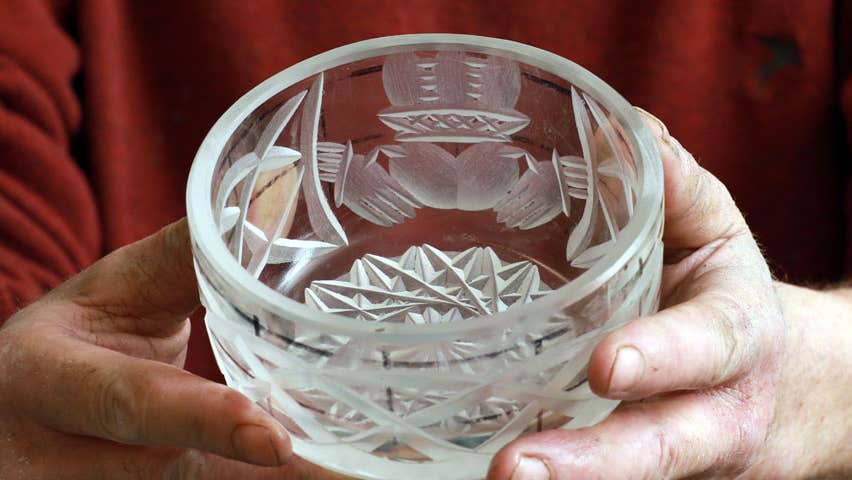 A close up of a crystal bowl with someone holding it