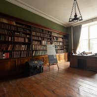 View of a library with wooden book cases and a desk