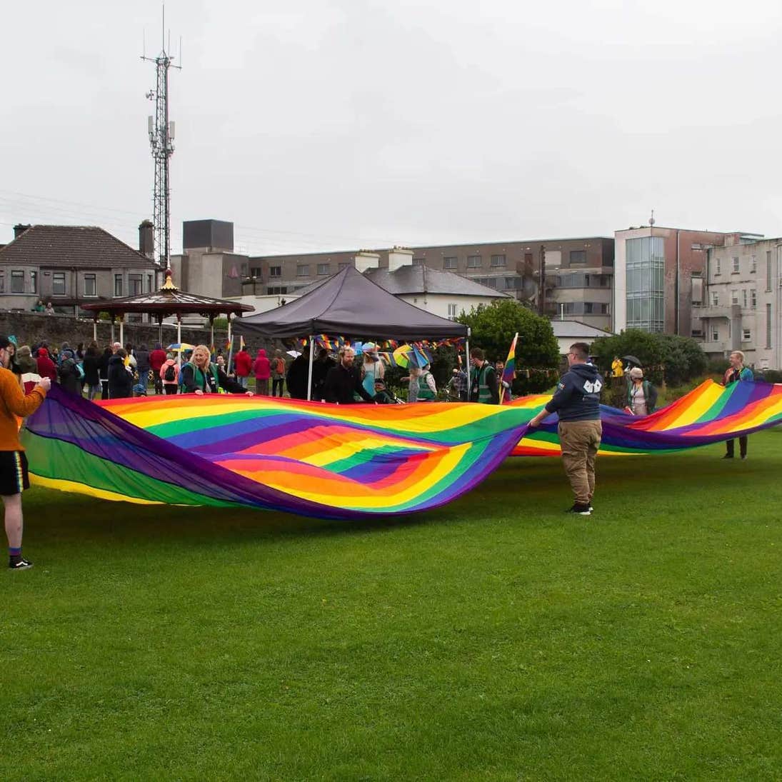 A large group of people laying out a large Pride flag during Galway Pride.
