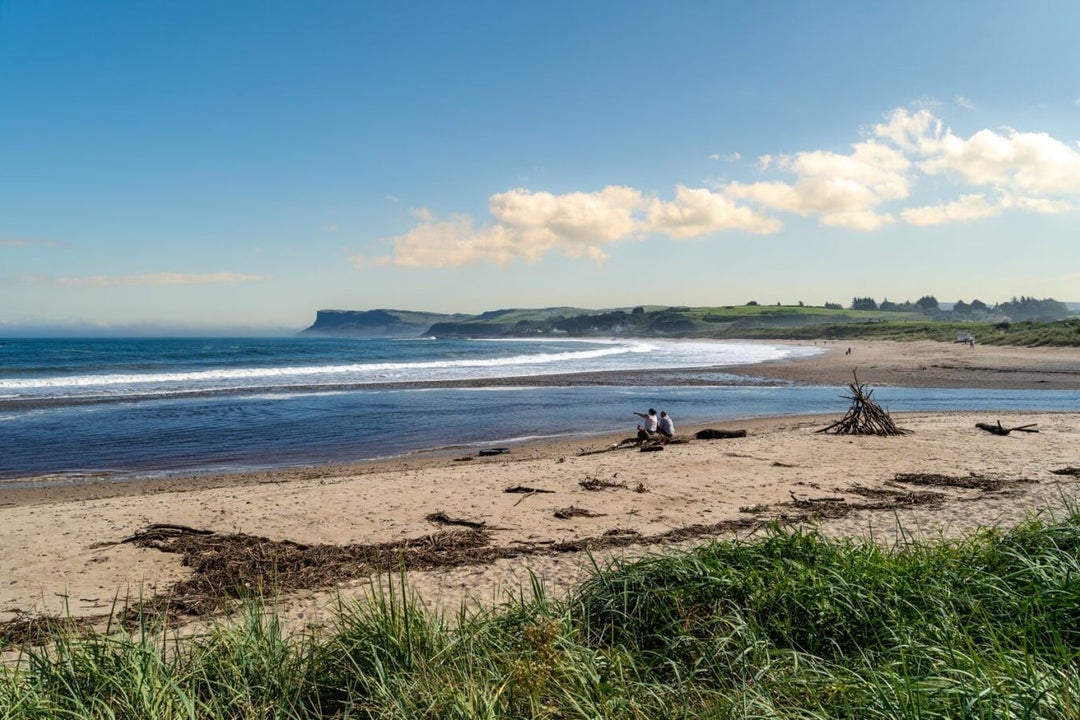 Sandy beach with two people sitting on it