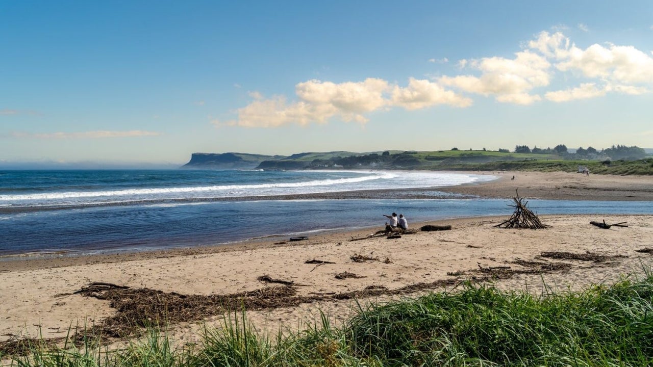 Sandy beach with two people sitting on it