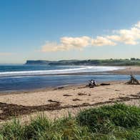 Sandy beach with two people sitting on it
