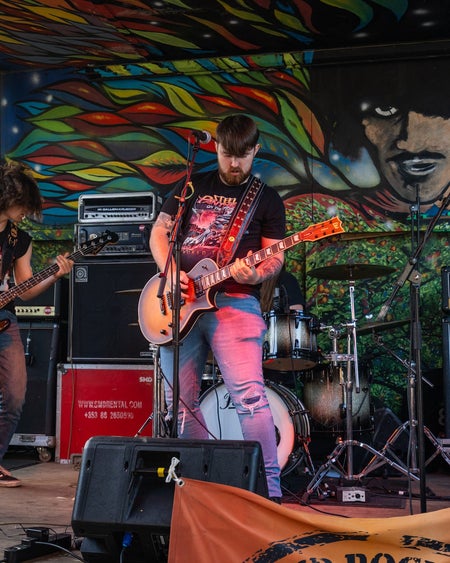 A band playing their guitars on the stage in The Bloody Stream