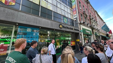 A tour guide standing outside a modern city building with a group of people