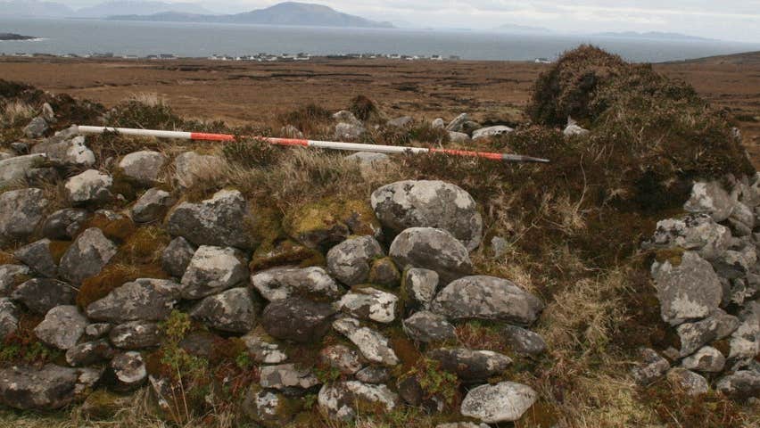 An ancient stone wall with a view beyond of hills and bogland