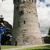 Two people pointing their camera up at a tower