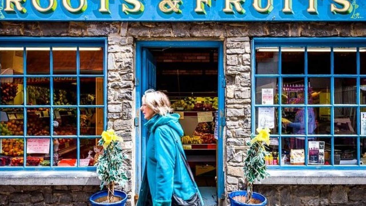 A stone clad shop front with old style green window panes and signage