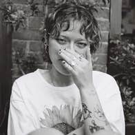 Black and white photo of person covering their nose with a hand.