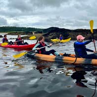 Three kayaks with kayakers and guide on water