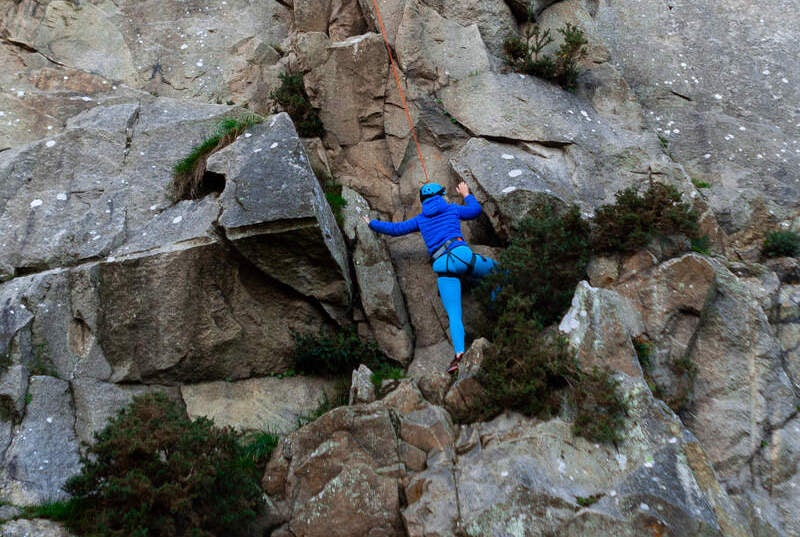 Image of a person climbing a rock face.