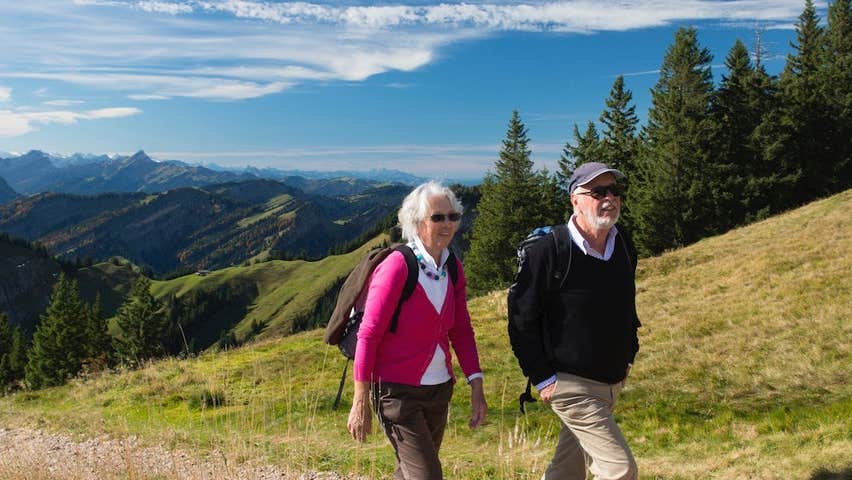 Two adults hike up a hill in the countryside