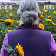 Film poster showing rear view of women in purple jacket standing in a field of sunflowers