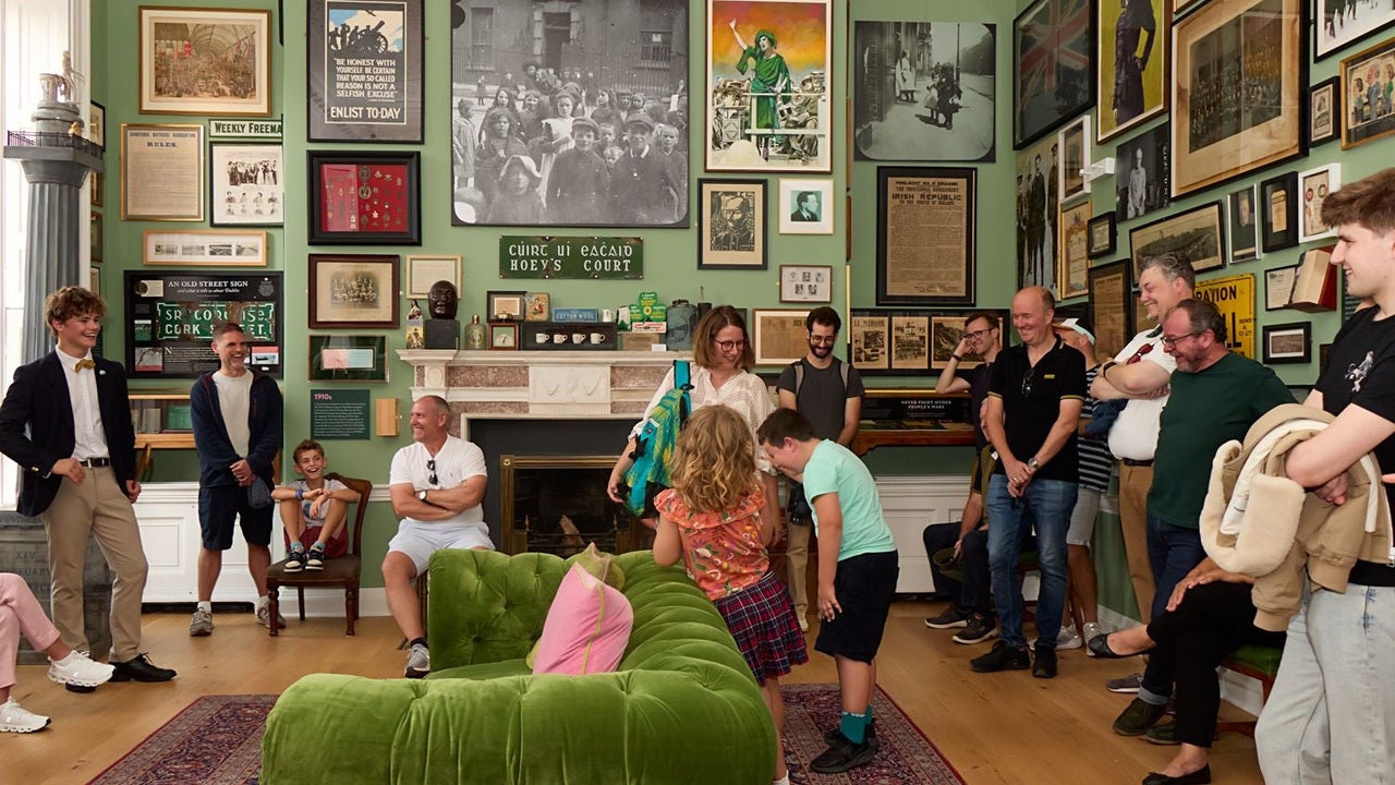 Group of people gathered in a cosy picture filled room listening to a guide