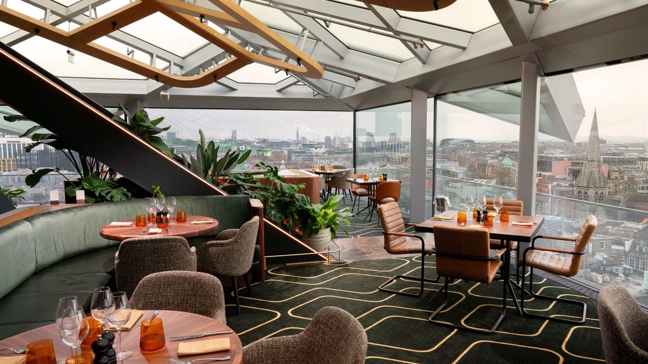 A rooftop dining space with sweeping daytime views across the city skyline