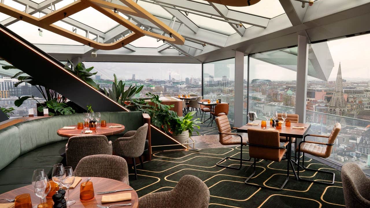 A rooftop dining space with sweeping daytime views across the city skyline