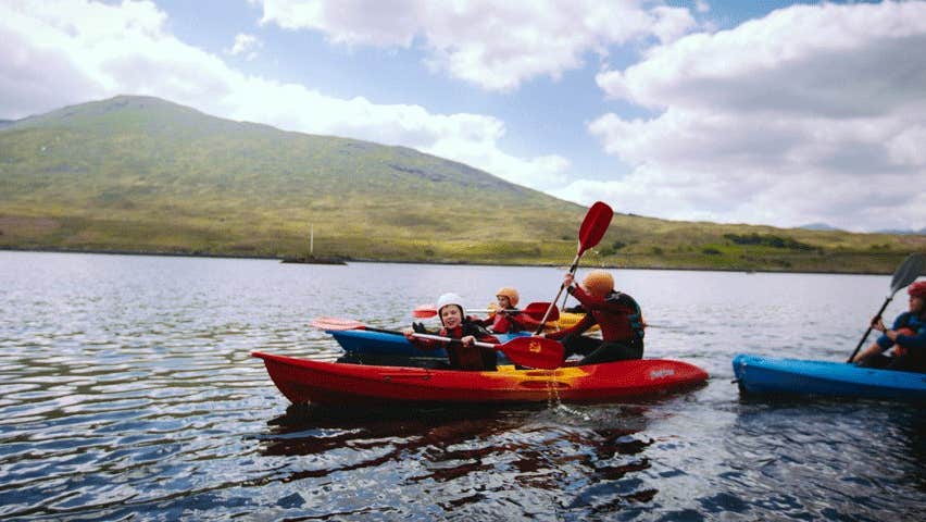 A family of kayakers on a lake with a mountain in the background