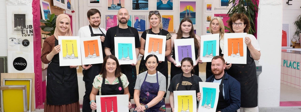 Group of people holding colourful prints posing for a picture
