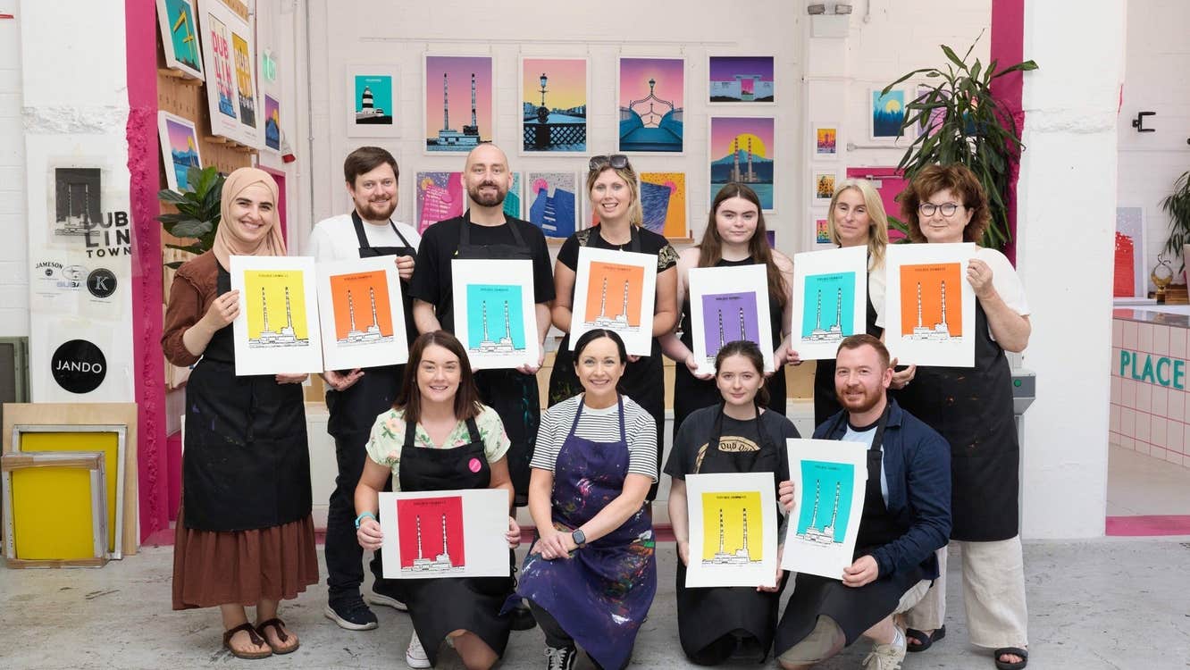 Group of people holding colourful prints posing for a picture