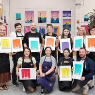 Group of people holding colourful prints posing for a picture