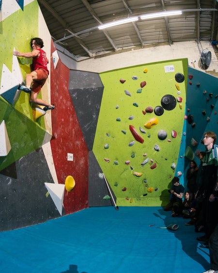 A man on a climbing wall with two people watching
